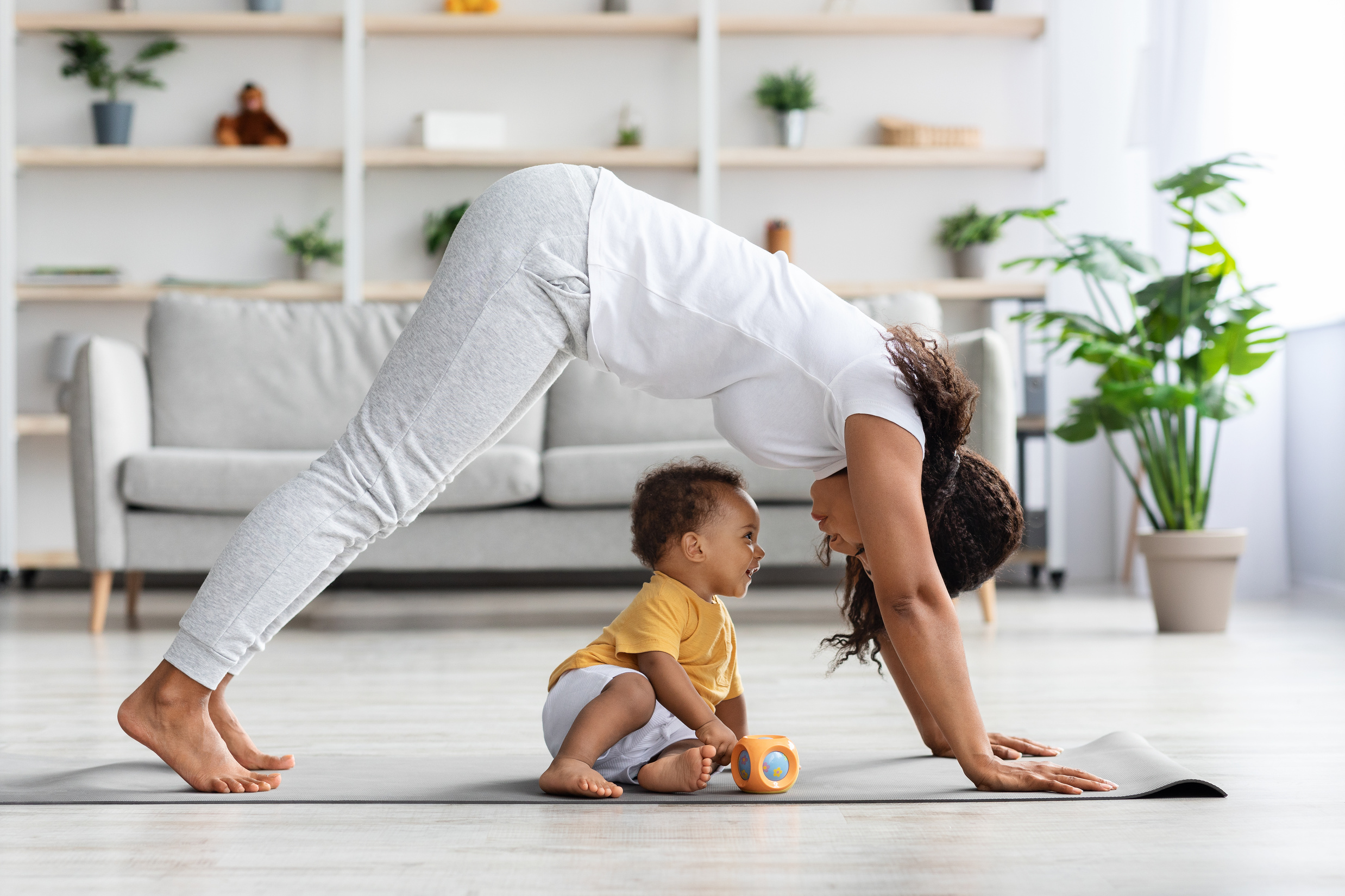 Young African American Woman Practicing Yoga with Little Baby Son at Home